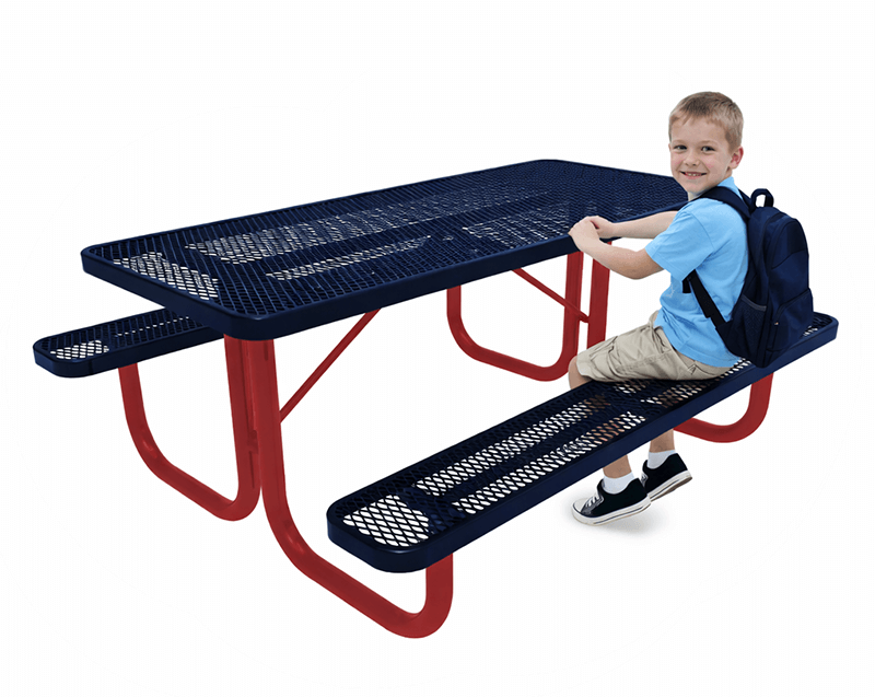 Elementary school student seated at a child-height rectangular steel picnic table with perforated metal top and benches.